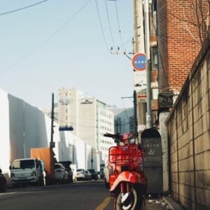 a red scooter parked on the side of a street